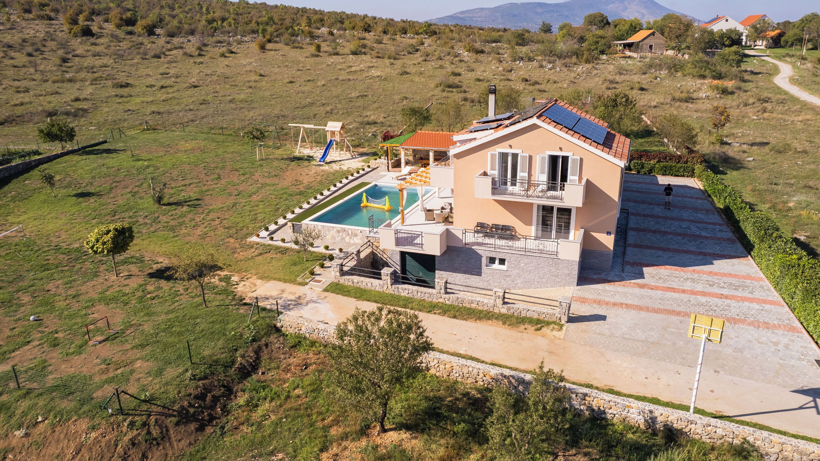 Una casa moderna con piscina, un patio cubierto y vistas al campo circundante.