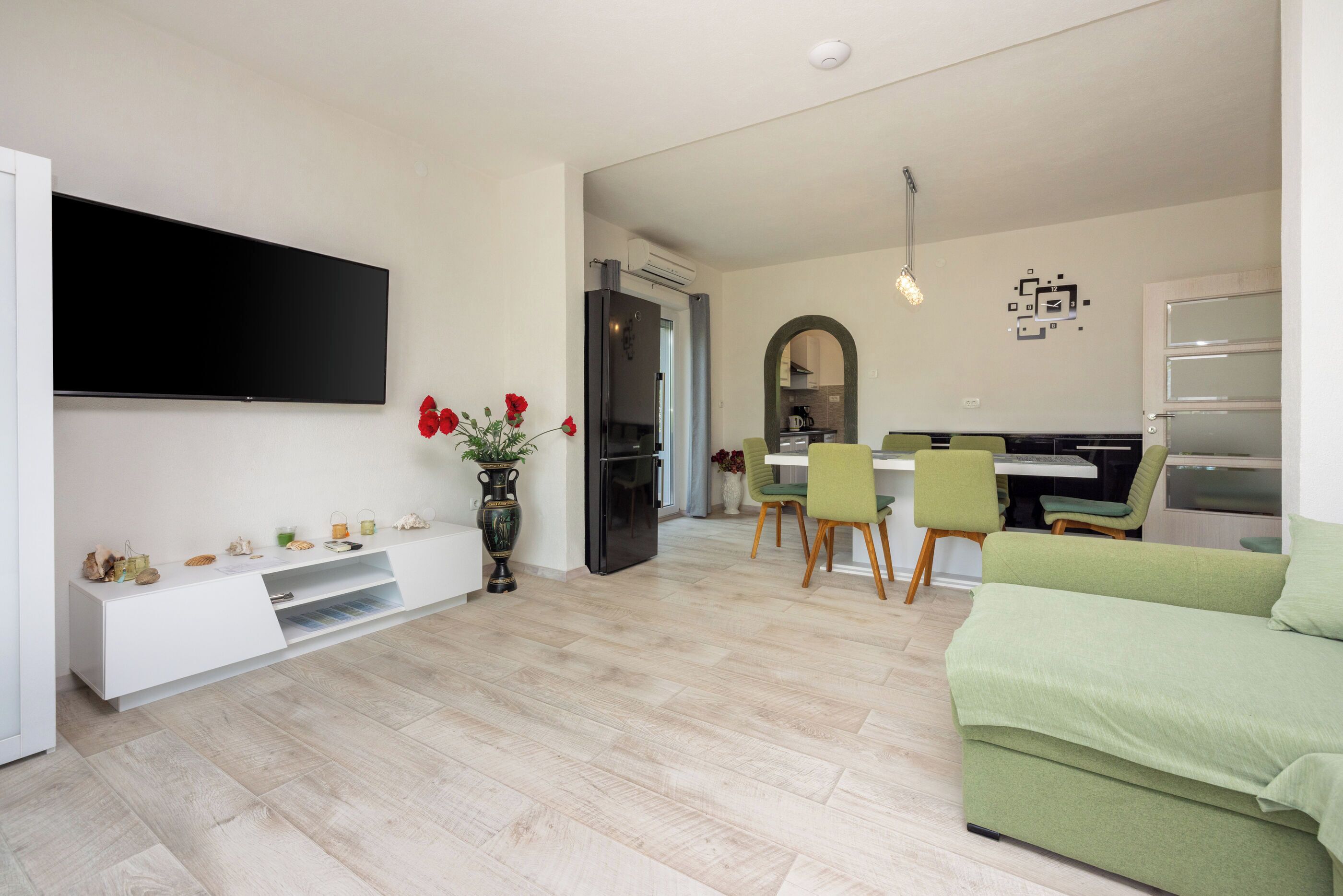 Un salon moderne doté d’un téléviseur à écran plat, d’un canapé et d’un coin repas avec des chaises et une table.