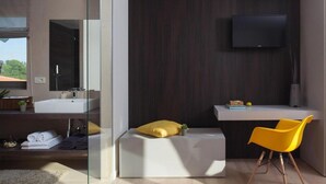 A modern bathroom with a large mirror, a white sink, and a yellow chair. - Villa Royal Green (Rasa)