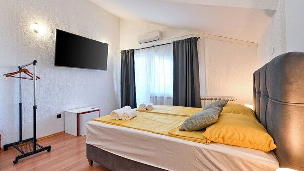 A bedroom with a bed, a TV mounted on the wall, a desk, and a wardrobe. - Villa Home2b (Bjelovar)