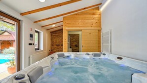A hot tub with a wooden ceiling and a brick wall in the background. - Villa Home2b (Bjelovar)