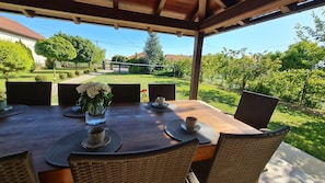 An outdoor patio with a wooden table set for four, surrounded by wicker chairs.