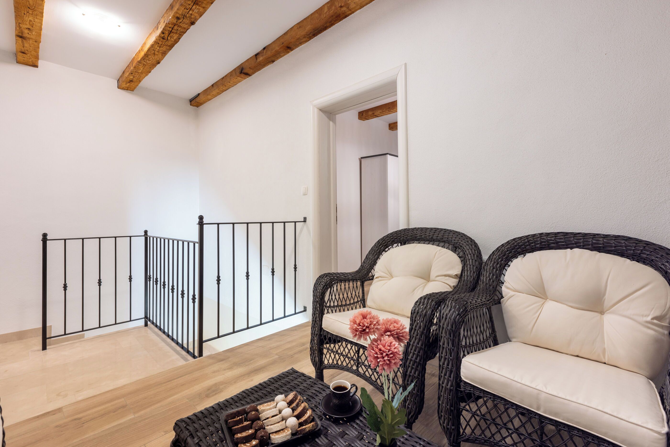 Una sala de estar amoblada con sillas de mimbre, una mesita con aperitivos y una escalera de madera.