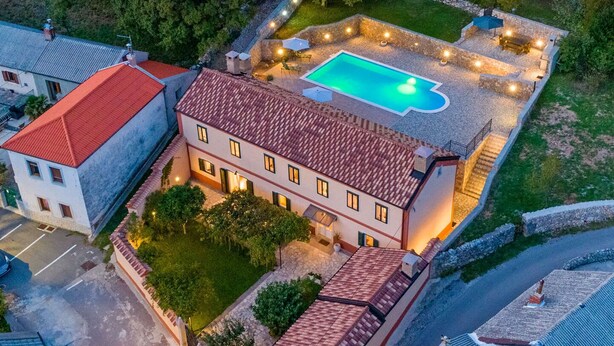 A two-story building with a swimming pool on the second floor, surrounded by stone walls and outdoor lighting. - Villa Eirene (Kraljevica)