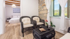 A room with wicker furniture, a bed, a table with pastries, and a view through a window with curtains. - Villa Eirene (Kraljevica)