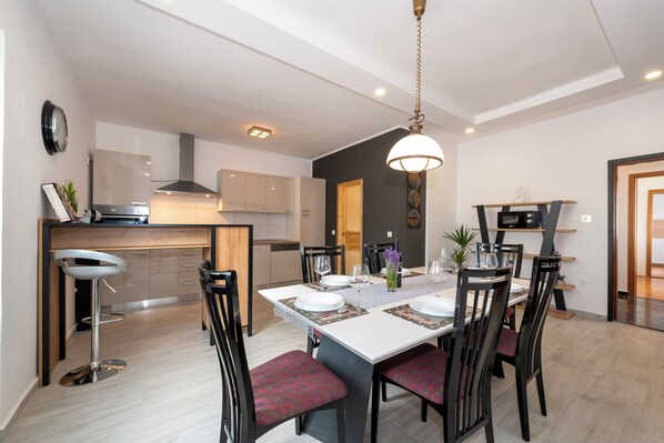 Une cuisine moderne avec un coin repas, comprenant un îlot central, des tabourets de bar et un luminaire suspendu.