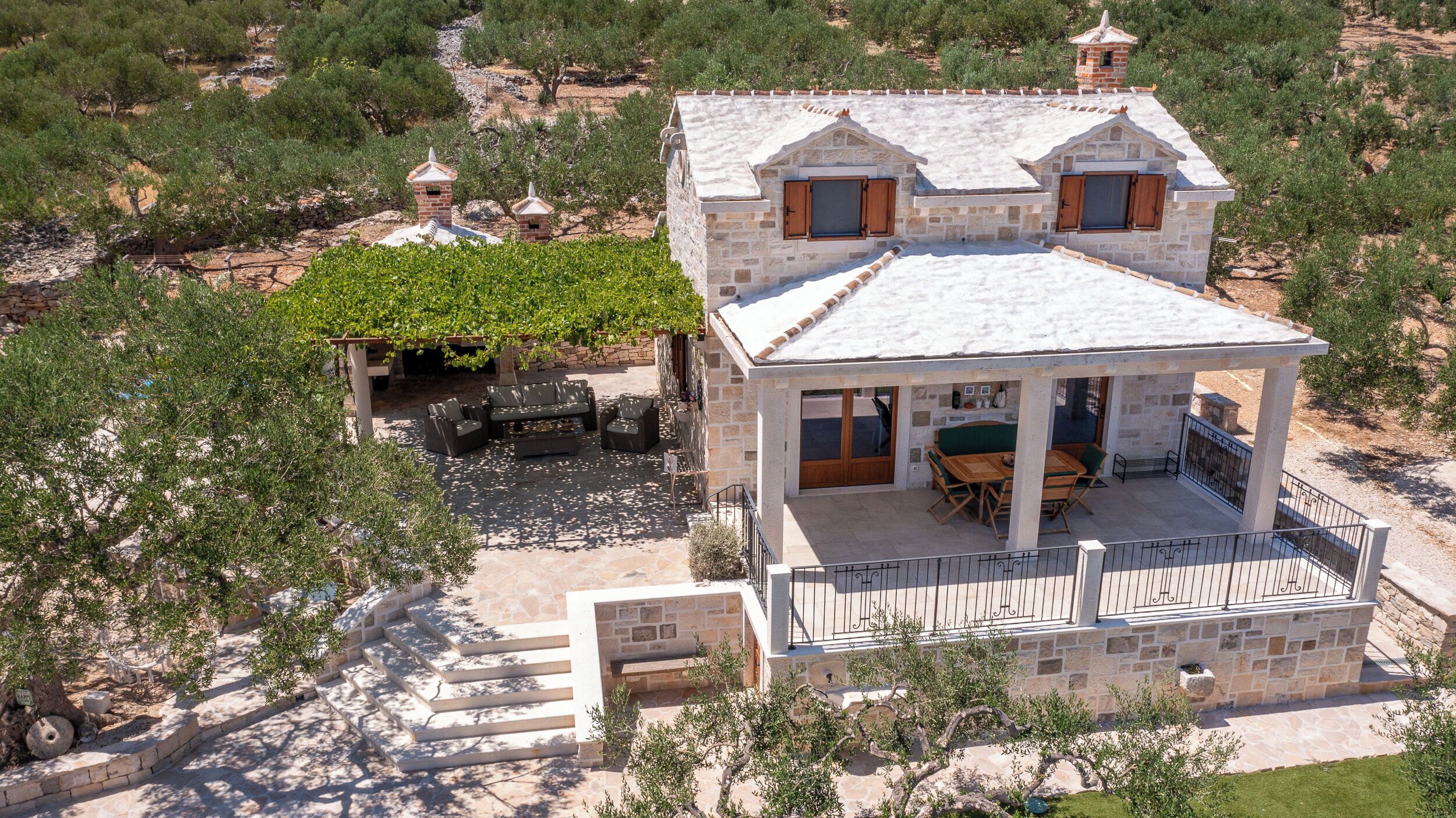 A stone villa with a covered patio, outdoor seating, and a view of the surrounding landscape.