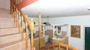 A staircase with wooden balusters leading to a kitchen area with stone countertops and white cabinets. - Villa Casa With Indoor Pool (Dugi Rat)