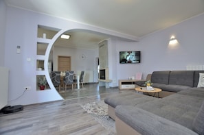 A modern living room with a grey sofa, a coffee table, and a TV mounted on the wall. - Villa Daris (Sveta Nedelja)