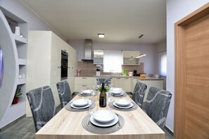 A dining area with a wooden table set for six, surrounded by chairs. - Villa Daris (Sveta Nedelja)