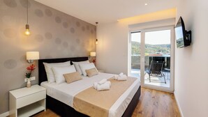 A hotel room with a bed, nightstand, lamp, and a TV mounted on the wall. - Villa Dal' Mares (Marina)