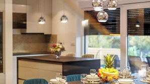 A modern dining area with a dark wooden table set for four, blue upholstered chairs, and a fruit centerpiece. - Villa Dal' Mares (Marina)
