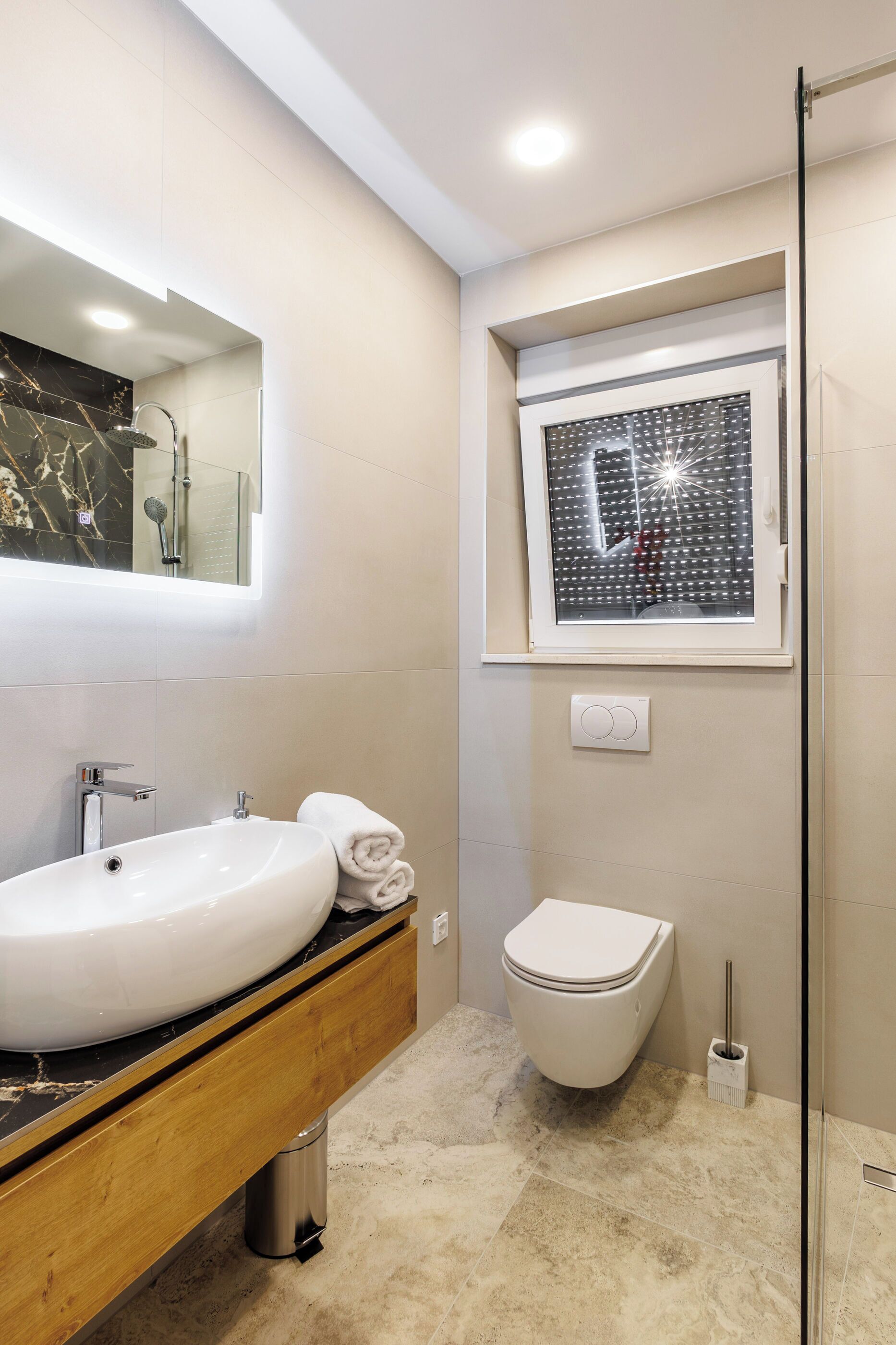Une salle de bain moderne avec un grand lavabo blanc, des toilettes et une douche à parois de verre.