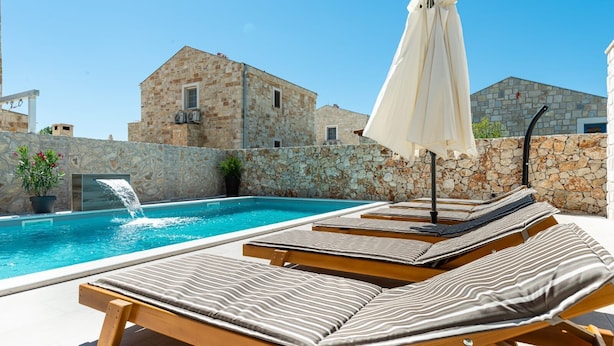 Zona junto a la piscina con sillones de descanso y una fuente.