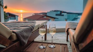 Two lounge chairs with a view of the sunset over the ocean and buildings in the background. - Villa Miracle (Rogoznica)