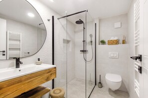 Ein modernes Badezimmer mit einer Duschkabine, einem Holzwaschtisch, einer weißen Toilette und einem Handtuchhalter.