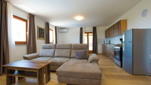 Un'ampia zona giorno con un divano componibile, un tavolino in legno e una cucina con elettrodomestici moderni.