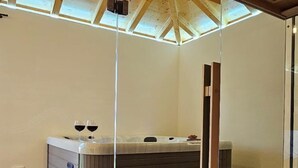 Ein moderner Wellnessraum mit Whirlpool, Holzboden und einer Dachfenster.