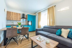 Ein modernes Wohnzimmer mit einem grauen Sofa, einem Holztisch und einem Essbereich mit Tisch und Stühlen.