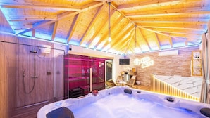 Ein Spa-Raum mit Holzboden, einer Whirlwanne und einer Glaseinfassung mit rosafarbenem Licht.