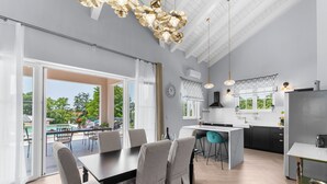 Cocina moderna con una isla grande, comedor con mesa y sillas, y vistas a una piscina y vegetación al exterior.