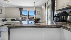Una cocina moderna con encimera de mármol, cafetera y vistas al exterior.
