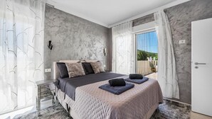 Un dormitorio con una cama grande, una mesita de noche, una ventana con cortinas y vistas al exterior.