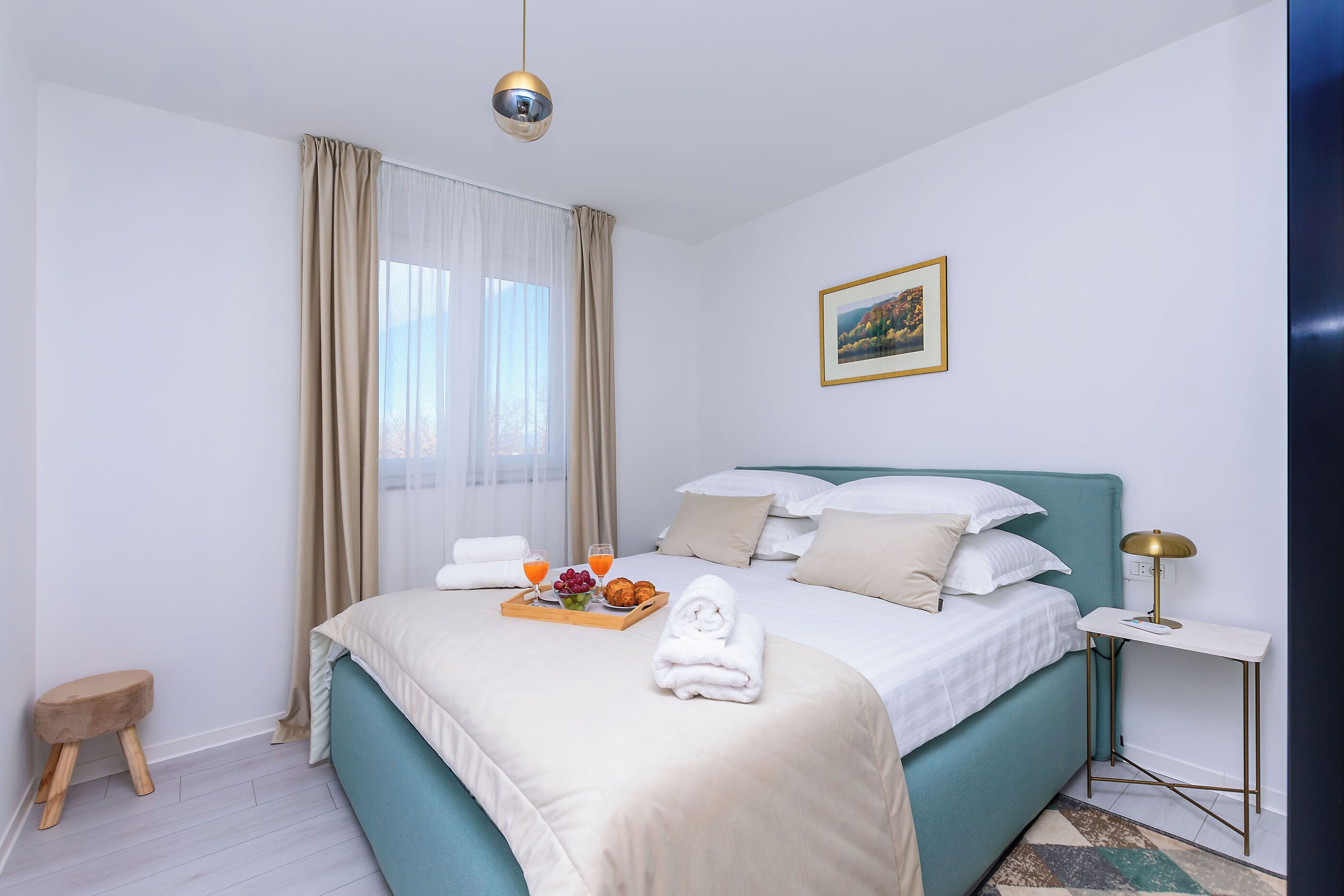 Una habitación de hotel ordenada con una cama, una mesita de noche y un taburete pequeño.