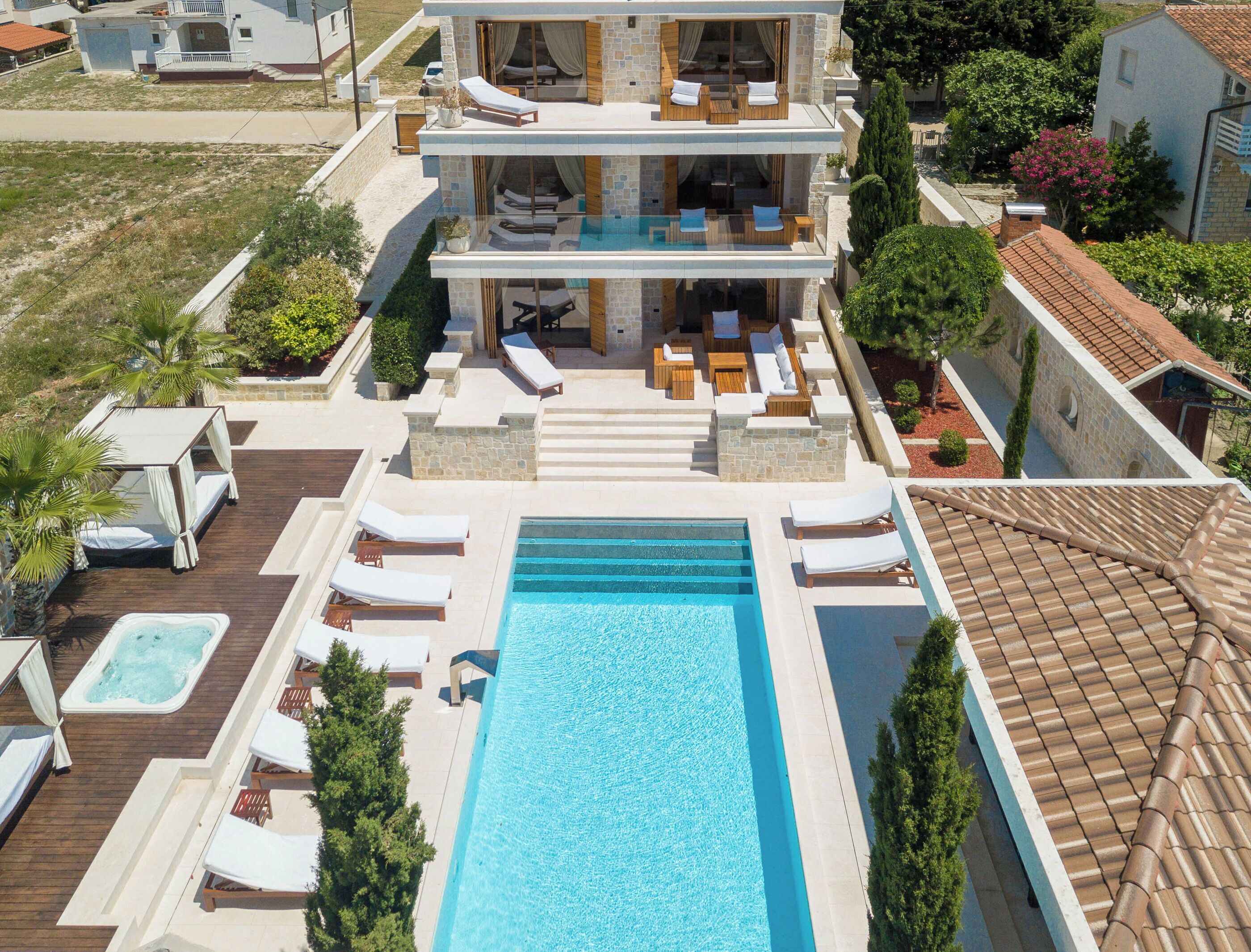 Una casa a due piani con piscina, area relax esterna e giardino.