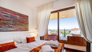 A hotel room with two beds, a large abstract painting, and a balcony with a view of the city. - Villa Nena (Polaca)