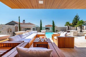 Ein Poolbereich mit Holzmöbeln, einer Steinwand und freiem Blick auf den Pool.