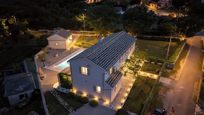 Ein zweistöckiges Haus mit Swimmingpool, umgeben von einem gepflegten Garten und einer gepflasterten Auffahrt.