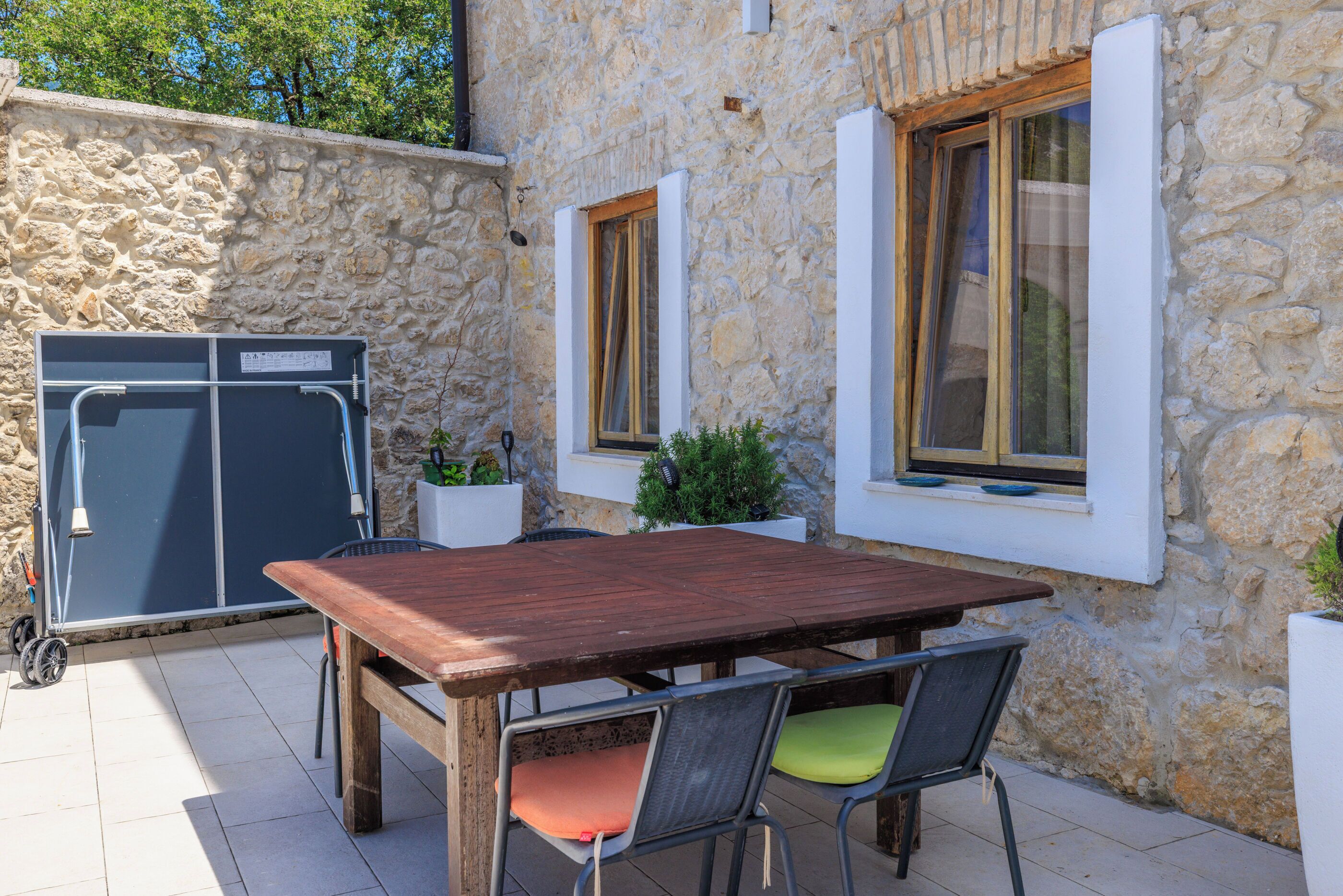 A stone building with a wooden table and chairs, a small window, and a white wall.