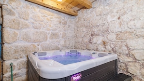 A hot tub with a wooden frame and stone walls, a wooden ceiling, and a step leading into the tub. - Villa Stone Castle (Vinodol)