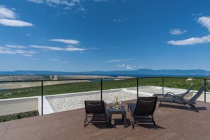 A terrace with a table, two chairs, and a bottle of wine. - Villa El Viento (Kraljevica)