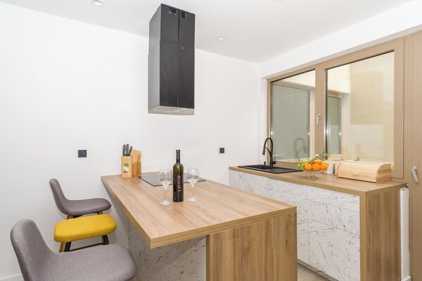 A compact kitchen with a wooden countertop, a built-in oven, and a large window. - Villa El Viento (Kraljevica)