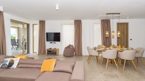 Een moderne woonkamer met een bank, eettafel, stoelen en een televisie.