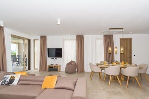 A modern living room with a sofa, dining table, chairs, and a TV. - Villa El Viento (Kraljevica)