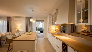 A modern kitchen with a central island, white cabinetry, and pendant lighting. - Villa Gospoja (Rogoznica)
