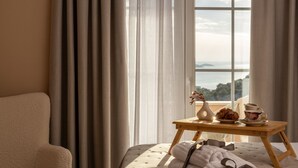 A bedroom with a bed, a bedside table with a croissant, a cup, and a vase with flowers. - Villa Gospoja (Rogoznica)
