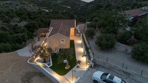 A house with a paved driveway, a lawn, and a car parked in front. - Villa Gospoja (Rogoznica)