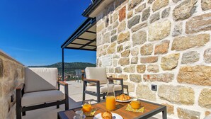 A stone wall, outdoor seating, and a table with breakfast items. - Villa Mare (Marina)