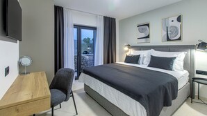 A modern hotel room with a large bed, a desk, a chair, and a TV. - Villa Mare (Marina)