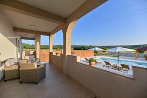 A spacious balcony with a pool, wicker furniture, and potted plants. - Villa Benedicta (Pakostane)
