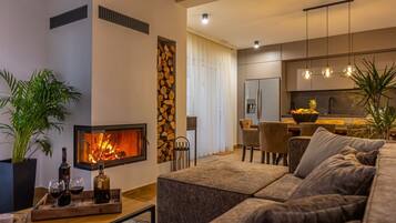 Una sala de estar moderna con chimenea, un sofá, una mesa de centro y un comedor con sillas y una mesa.