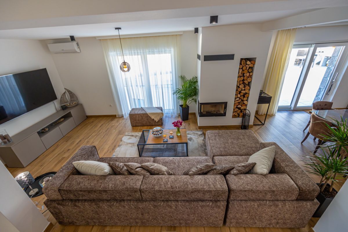 Ein modernes Wohnzimmer mit einer großen Eckcouch, einem Flachbildfernseher, einem Couchtisch und einem Kamin.