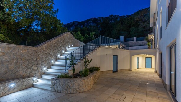 Ein modernes Gebäude mit Naturstein-Fassade, einer Treppe, die zu einem zweiten Stock führt, und einem gut beleuchteten Außenbereich mit Fliesenböden.