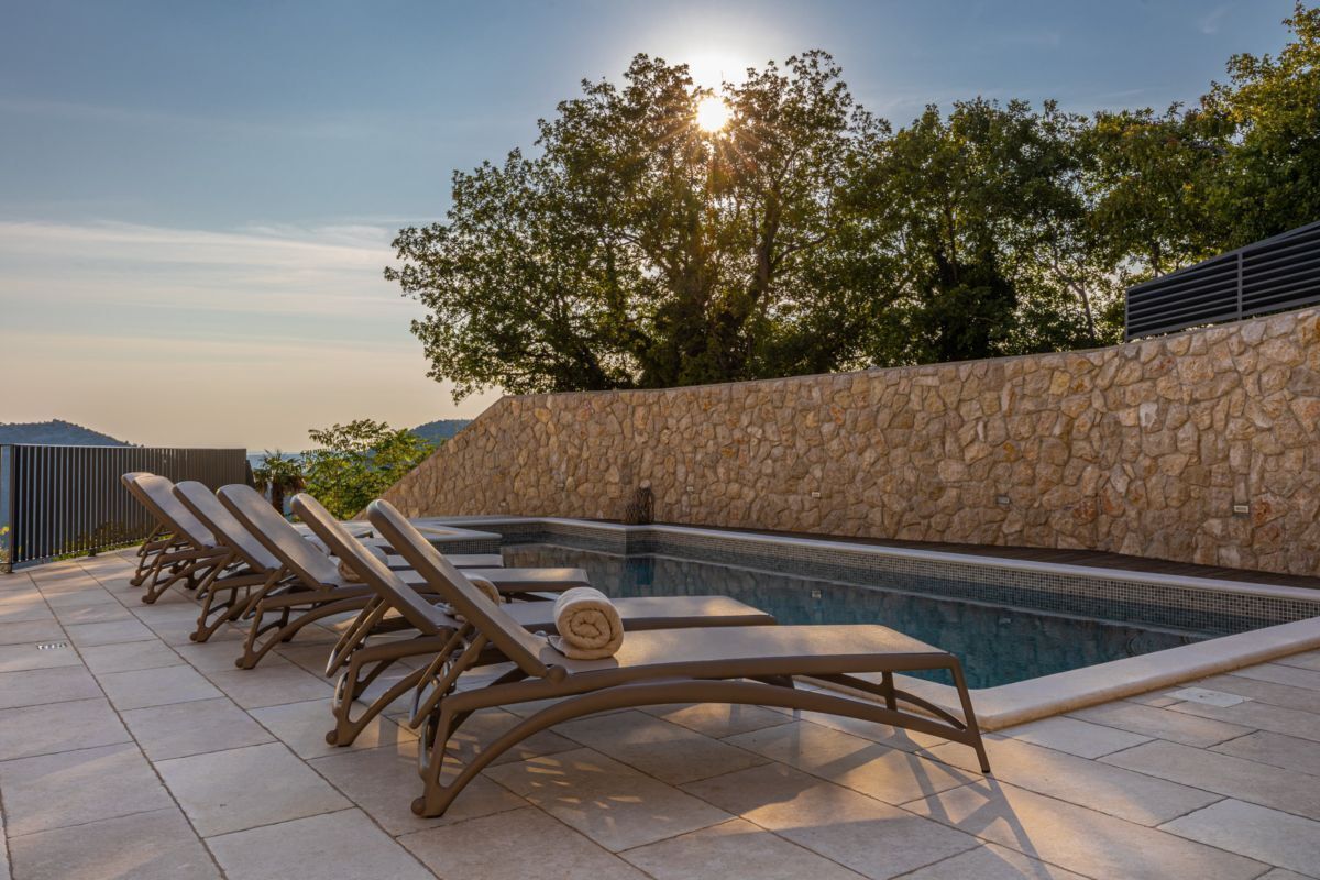 A poolside area with lounge chairs and a stone wall.