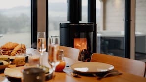 A dining table with breakfast items, a glass of juice, and a coffee maker. - Cabin Chalets House THREE (Geisa)