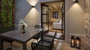 Un espace extérieur aménagé pour les repas, avec une table, des chaises et un vase de fleurs.